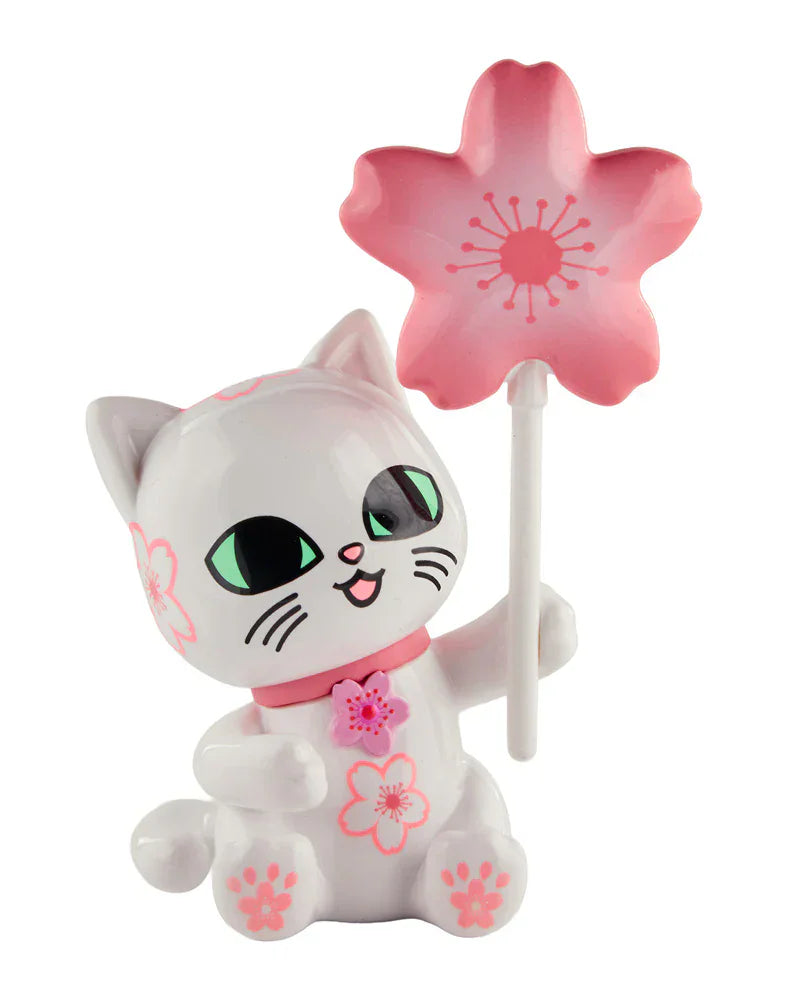 A white cartoon cat figurine from the Tokidoki Cherry Blossom Cats - Single Blind Box by Tokidoki holds a pink cherry blossom wand, with pink flower patterns on its body and collar—perfect for celebrating cherry blossom season.