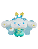 A cute cartoon with long ears, blue wings, and flower accents holding a green figure and a flower—perfect for fans of the Rotofugi Tokidoki x Hello Kitty and Friends Butterfly Garden Blind Box collectible toys.