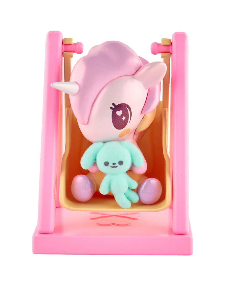 The tokidoki Baby Unicorno - Swingin' Baby Bunny (Special Edition) features a pastel-themed Baby Unicorno figurine holding a plush toy, sitting on a pink swing.