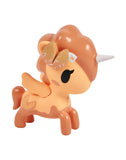 The Tokidoki Fortune Cookie Unicorno Blind Box features a surprise orange-and-cream unicorn figure with wings, a white horn, and a donut-shaped yellow mane, shown standing on a white background.