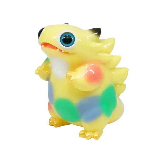 Tokke — Yellow Dots by The Little Hut (HK) is a small, yellow, dragon-like kaiju toy with blue eyes, colorful patches, and a spiked back. It stands upright on two legs against a white background.