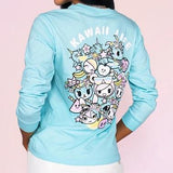 A woman wearing a blue long-sleeve t-shirt with kawaii characters on it, featuring Donutella by tokidoki.