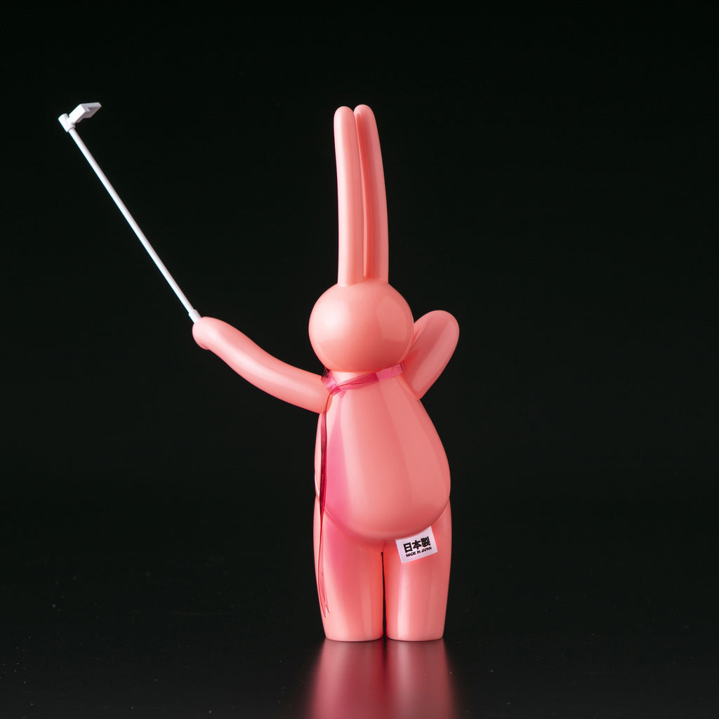 A pink bunny figurine holding a golf club, inspired by The Daily Flasher by mr. clement's Japanese vinyl style from Tomenosuke Shoten.