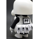 A close-up of a Playge (HK/US) Squadt GERM S006 [PEACE F***ER] vinyl toy figure wearing a backpack with the initials 