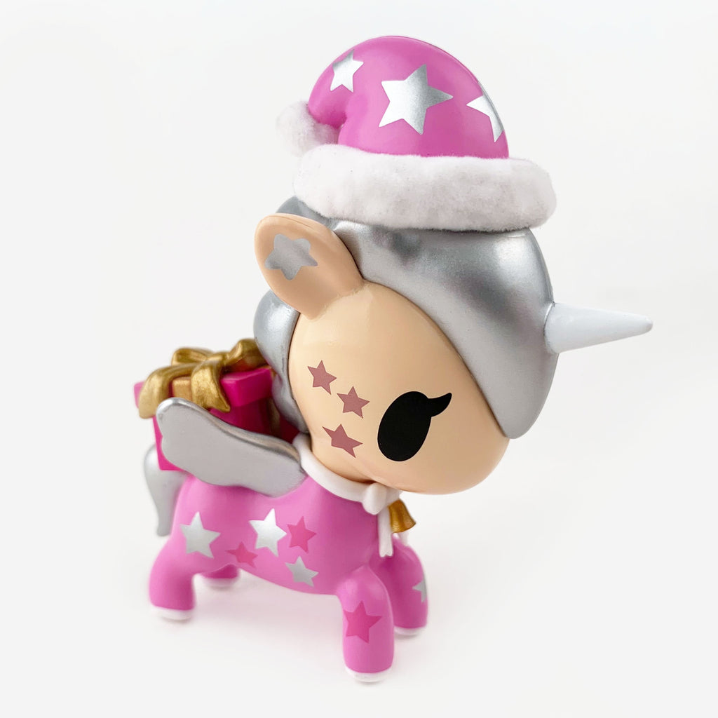 A pink tokidoki Holiday Unicorno Series 2 Blind Box chase figure with silver mane, wings, and horn, Santa hat, gold present, and white stars—an adorable collectible for any fan!.
