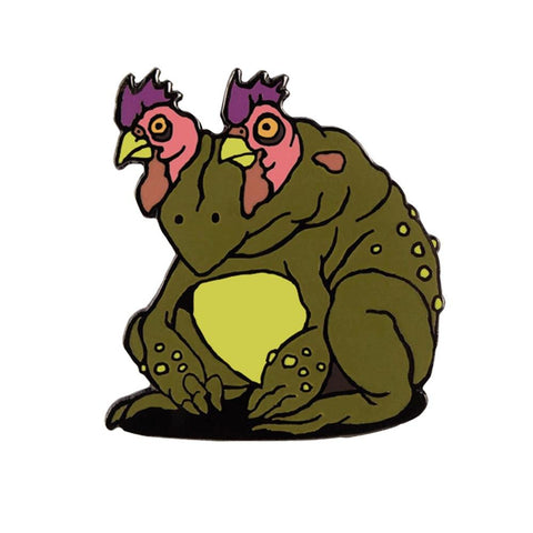An enamel pin design featuring The Artpin Collection - Chicken-Eyed Toad, a green frog with purple eyes, sitting on the ground.