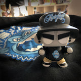 A Mad*L Citizen designer toy is sitting on top of a UVD Toys (US) t-shirt.