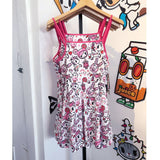 A tokidoki Pretty in Pink Skater Dress hanging on a hanger.