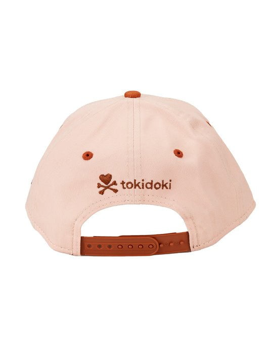 A pink Stay Wild Snapback by tokidoki with a skull and crossbones on it, featuring an adjustable strap for the perfect fit.