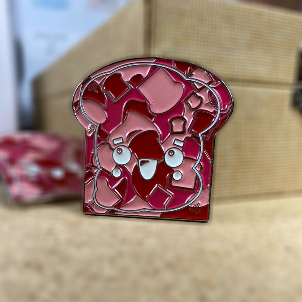 A slice of Toasty Strawberry Red Camo Enamel Pin with hearts on it nestled on a Bread and Buttery box.