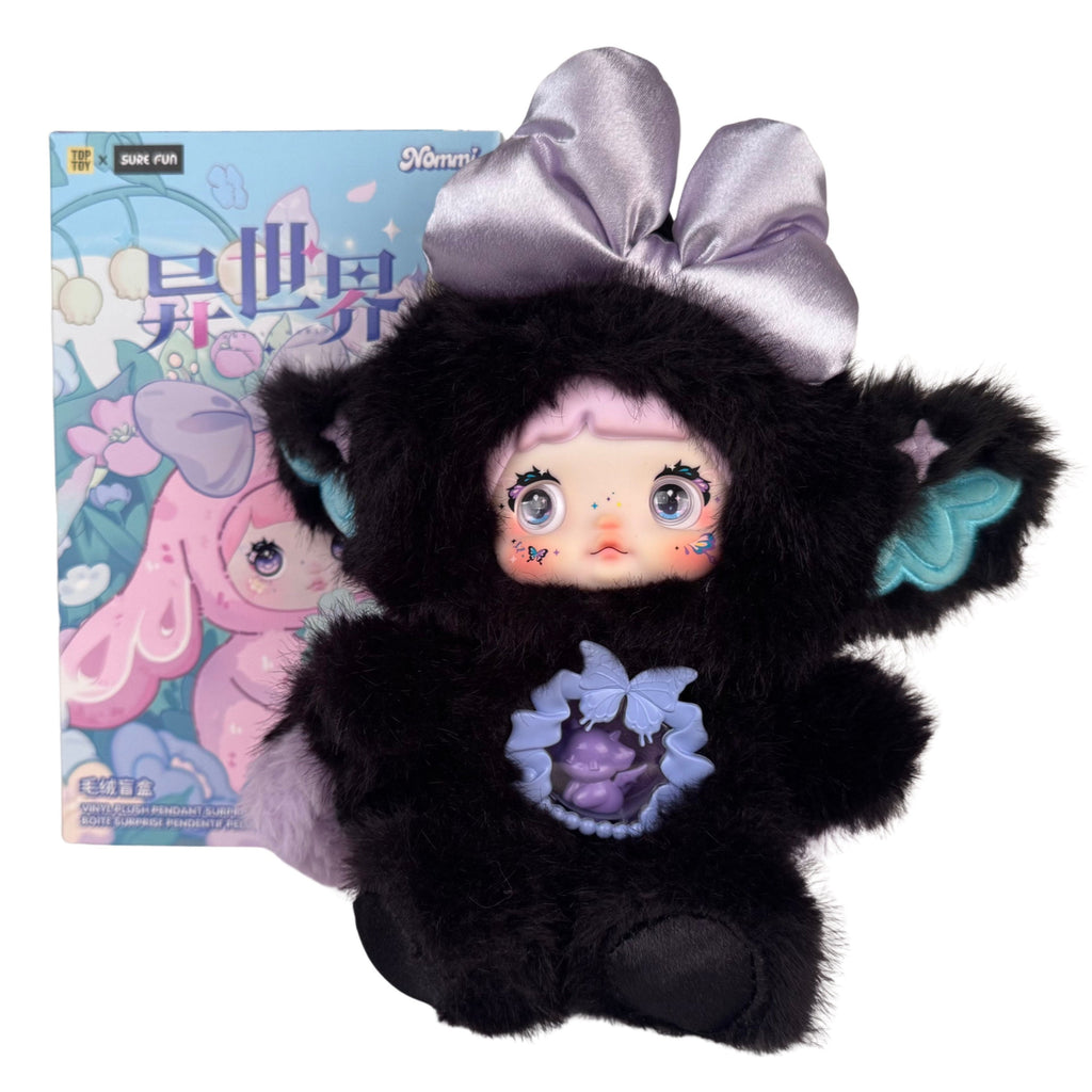 A Nommi Fantasy World Plush Blind Box doll in a black faux-fur hooded animal suit, featuring a lavender bow and a clear chest pendant, displayed in front of its illustrated product box.