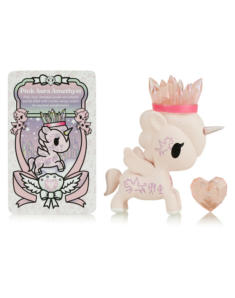 The Tokidoki Precious Unicorno - Pink Aura Amethyst figurine, featuring a crystal crown and heart-shaped crystal, exudes healing properties. The decorative card labeled 