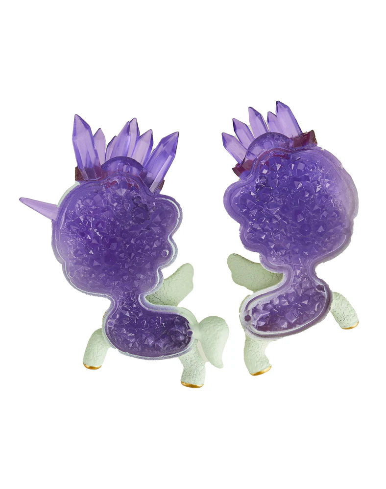 Two figures from the Tokidoki Precious Unicorno Blind Box by tokidoki, rendered in purple with crystal textures reminiscent of precious stones, face each other on a white background—a genuine collector's treasure.