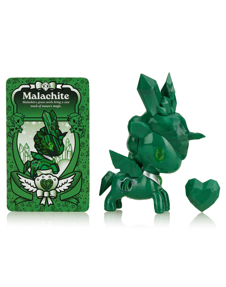 The tokidoki Precious Unicorno Blind Box features a green unicorn figurine with crystal elements, a heart-shaped piece, and a 