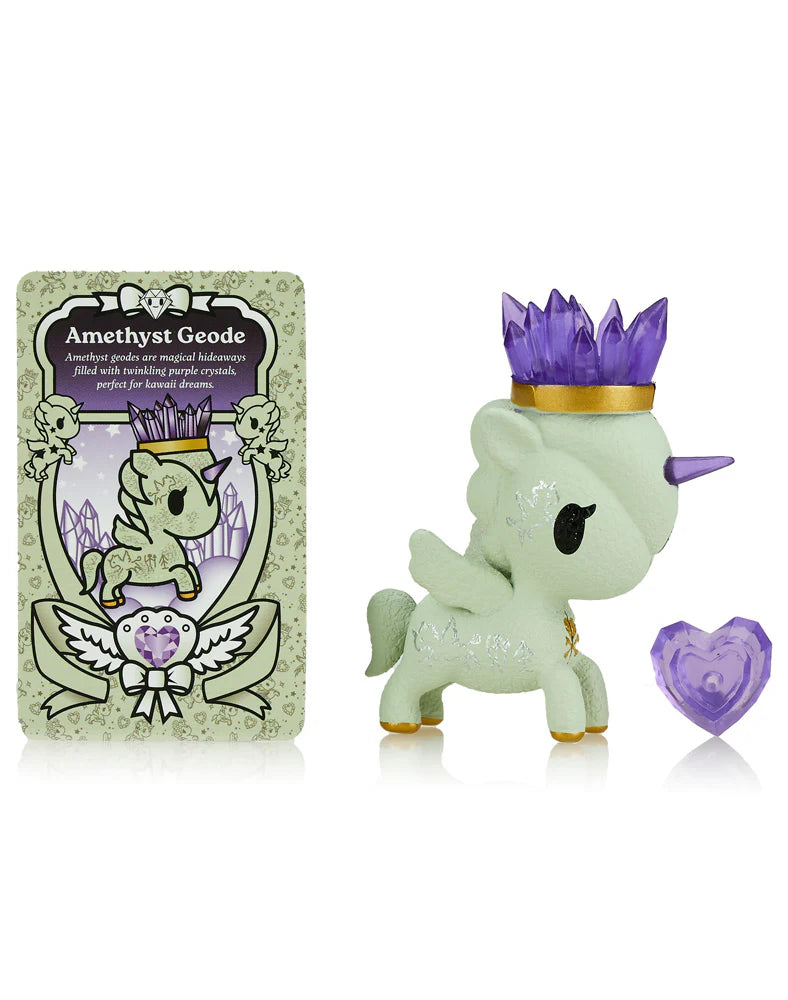 A Precious Unicorno figurine from the Tokidoki Blind Box, featuring a purple crystal crown, stands alongside an 