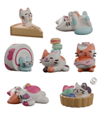 Seven Bake Me A Cat Blind Box figures by Kaleidos Creative are shown in dessert-themed poses—cheesecake, swiss roll, macarons, donuts, and fruit tarts—inspired by Kim-Joy’s Great British Bake Off designs on a white background.