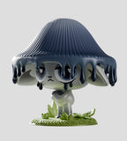 A gray Capkins figure with droopy eyes stands on grass, wearing a large dark mushroom cap that drips over its head—part of the Kaleidos Creative Capkins Series 1 Blind Box collection.