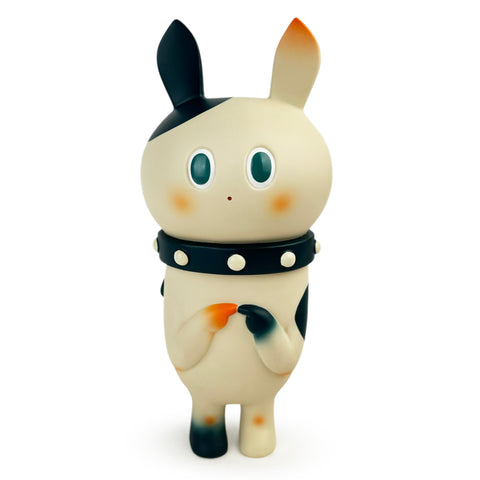 The Half — OG by How2Work (HK) is a cute, white cartoon character with large blue eyes and black accents. It stands upright, has rabbit-like ears, wears a studded black collar, and displays a shy expression.