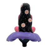 The Flower Girl collectible figure by UVD Toys (US) showcases a person with long, black hair adorned with flowers and stars, sitting cross-legged on a vibrant purple flower—an eye-catching gift for fans.