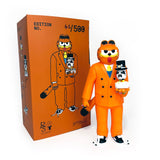 The Gangster Doodles GARF Vinyl Toy & Cassette Tape by Gangster Doodles features an orange-suited figure holding a doll, displayed next to an orange box with matching art—an eye-catching collectible for fans.