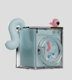 The Ghost Cat Blind Box by Kaleidos Creative features a playful blue washing machine with cartoon eyes, a music note door, a tail-like blue Ghost Cat, and a pink bird perched on top—collectible figures on a light gray background.