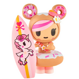 A bear-eared, pink-haired figurine with a flower lei holds a unicorn-and-heart surfboard—part of the tokidoki Hawaiian Ohana Blind Box collection.