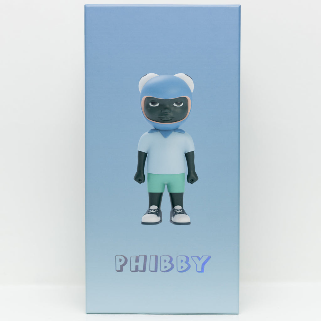 A rectangular box adorned with an illustration of a toy figure by Hebru Brand (US), featuring the figure in a blue helmet, light blue shirt, and green shorts. The word 