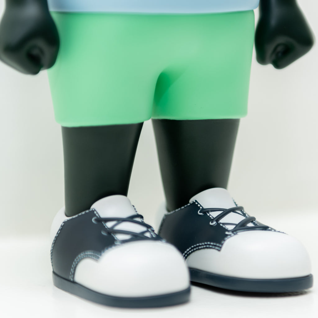 Close-up of the limited edition Phibby — Purple toy figure, by Hebru Brand (US), wearing green shorts and black and white shoes, inspired by one of Hebru Brantley's iconic characters.