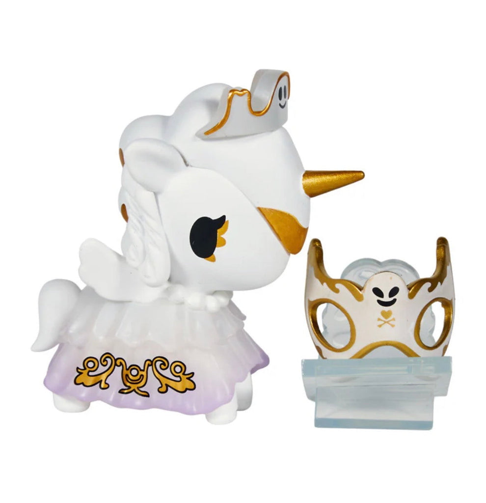 From Tokidoki's Unicorno After Dark Masquerade Blind Box, this collectible toy features a white unicorn figurine with gold and purple accents, displayed beside a matching crown accessory on a display stand.