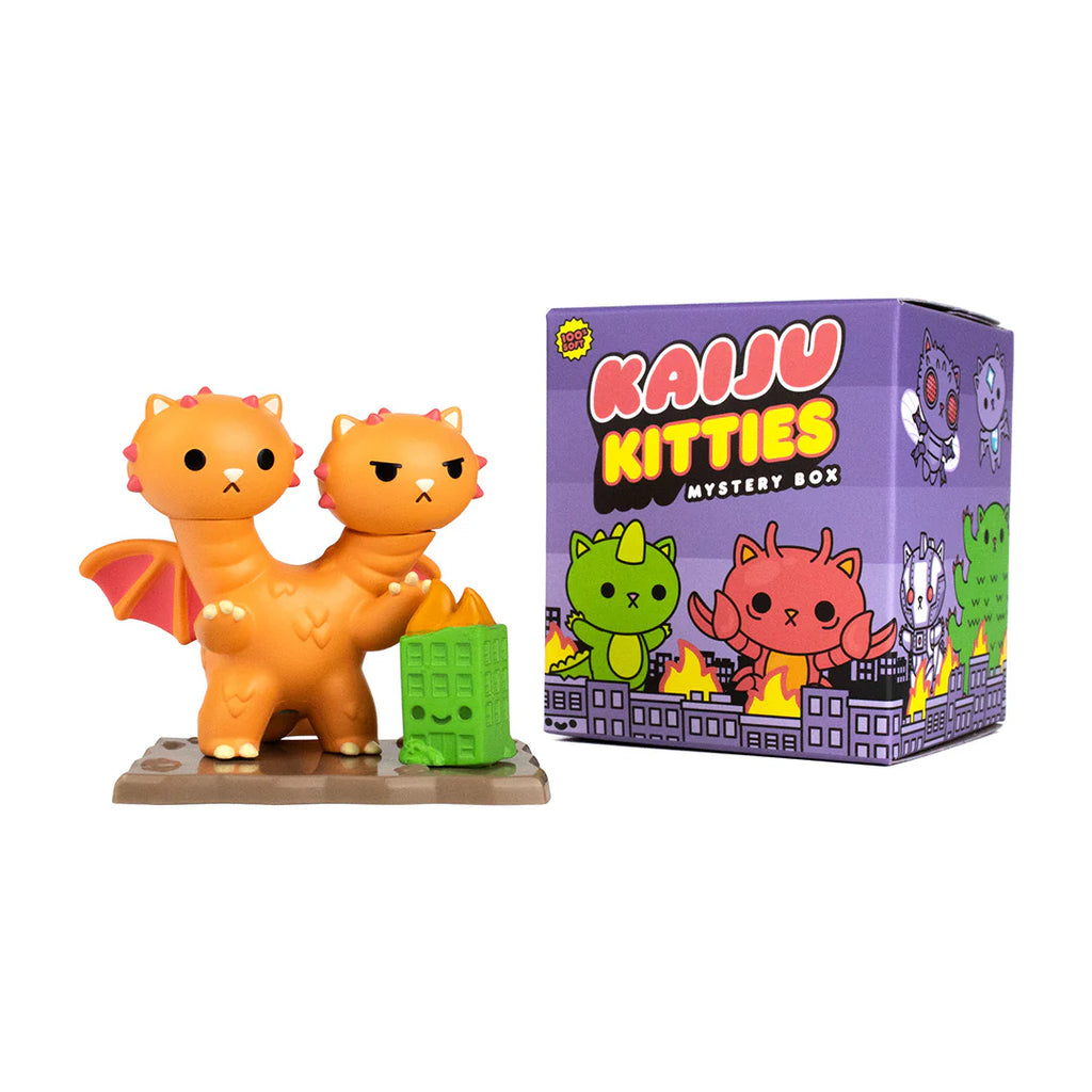 A two-headed, orange cat figurine with dragon wings stands next to a purple box labeled 