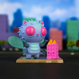 A colorful toy figurine of a bug-eyed creature with wings stands on a platform, next to a pink building with yellow details, with a blurred cityscape in the background. This charming collectible, reminiscent of destructive monsters from the 100% Soft Kaiju Kitties Blind Box, adds a playful twist to any collection.