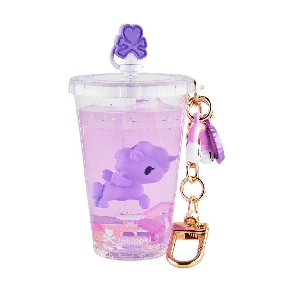 The tokidoki Beverage Besties Unicorno Blind Box keychain features a clear cup with a purple unicorn, purple lid and straw, gold hardware, and pink charm—perfect for fans and collectors.
