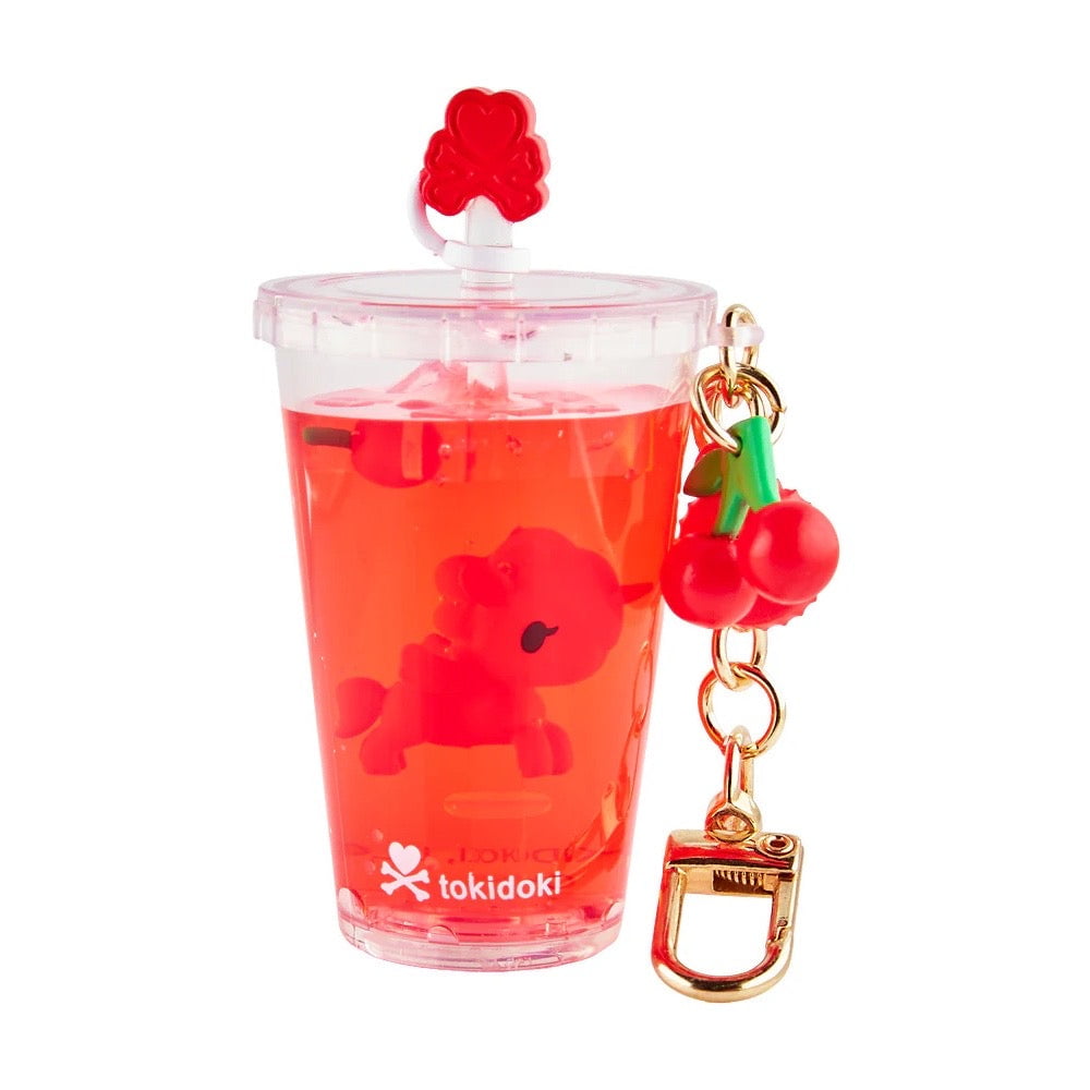 A clear cup-shaped tokidoki keychain featuring a red unicorn figure, cherry charm, gold clip, and the Tokidoki Beverage Besties Unicorno Blind Box logo—perfect for fans of collectible surprises.