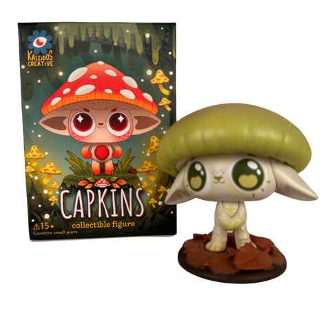 A Capkins Series 1 Blind Box figure from Kaleidos Creative—with a green mushroom cap—stands on its base beside the illustrated packaging showing a red-capped character and the Kaleidos Creative logo.