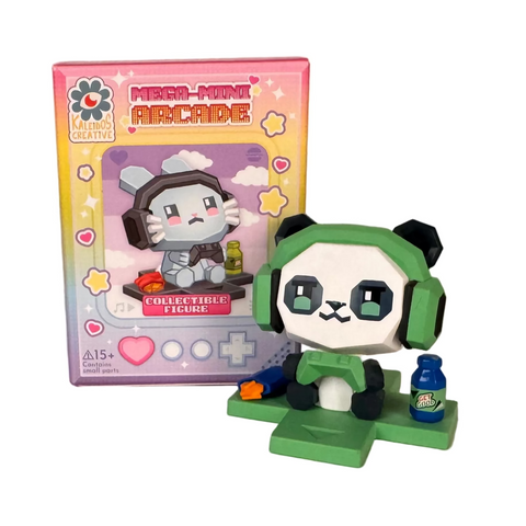 A green panda figurine with headphones sits on a game controller beside a drink, in front of a colorful Kaleidos Creative Mega-Mini Arcade Blind Box—one of the collectible gamer figures from this surprise series.