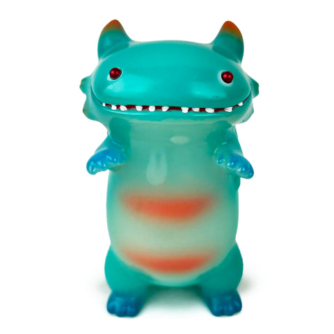 A small Byron — Year of the Dragon (Glow) toy from The Little Hut (HK) stands upright, featuring turquoise skin, red eyes, orange accents, and a wide grin with visible teeth.