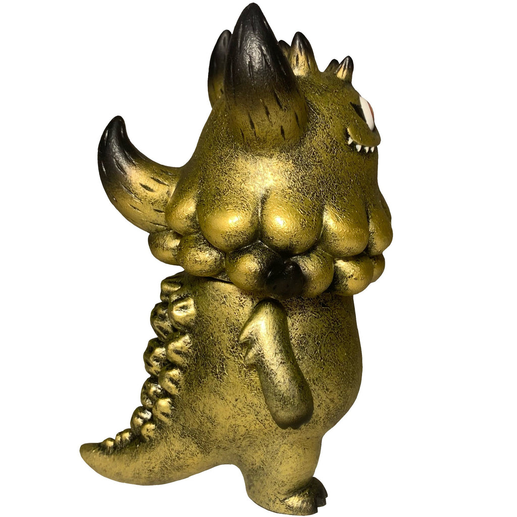 The Little Hut (HK) Rangeas Jr. - Gold Patina: A gold and black monster figure with a textured body, horns, spiked tail, and one visible eye is shown side view on white—an ideal collectible for fans.