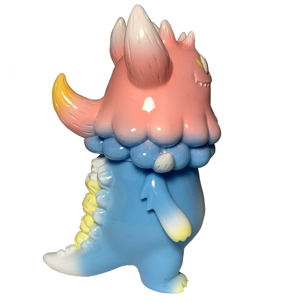 The Little Hut (HK) Rangeas Jr. - Light Blue/Pink features a pastel monster with a pink head, yellow-tipped horns and tail, and blue body, shown in profile on white—an ideal collectible for designer vinyl enthusiasts.