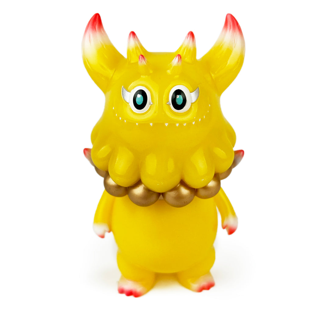 The Little Hut (HK) presents Rangeas Jr. — Golden Dragon: a yellow toy creature with horns, large eyes, toothy smile, ruffled collar, and red-tipped hands and feet.