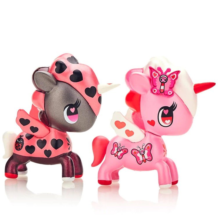 Two pink and black Unicorno Love Bugs 2-Pack toys, Lily and Coccinella by tokidoki (IT), resting on a white surface.