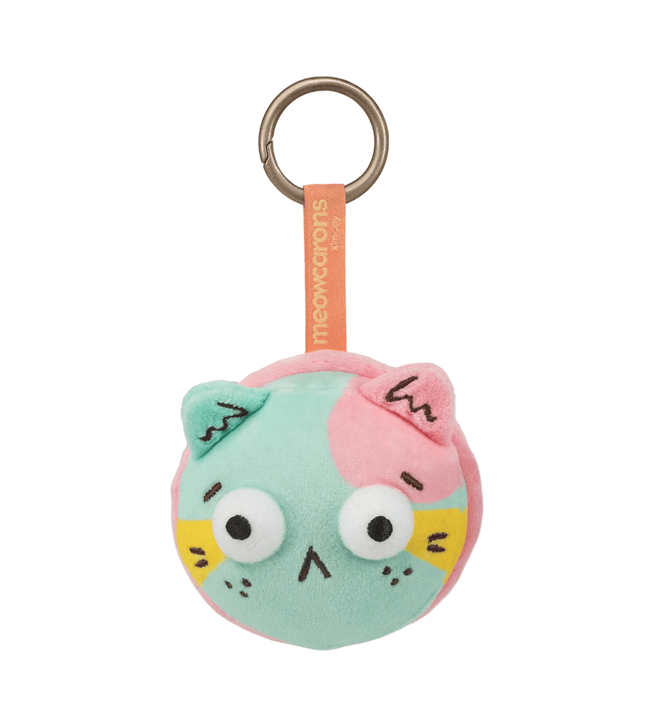 The Meowcaron Plush Bag Charm by Kaleidos Creative is a round, pastel cat-face accessory with a pink fabric loop and metal key ring—your whimsical bag companion inspired by Kim-Joy’s style.