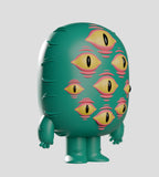 A green, cartoonish figure with multiple yellow and pink eyes stands upright against a gray backdrop—one of the quirky collectible figures from the Odds N Sods Blind Box by Kaleidos Creative.