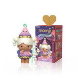 A Momiji — Sugar Plum Woods Blind Box collectible figure with a flower-shaped hat and purple wings standing next to its rectangular product box featuring illustrations of various characters.