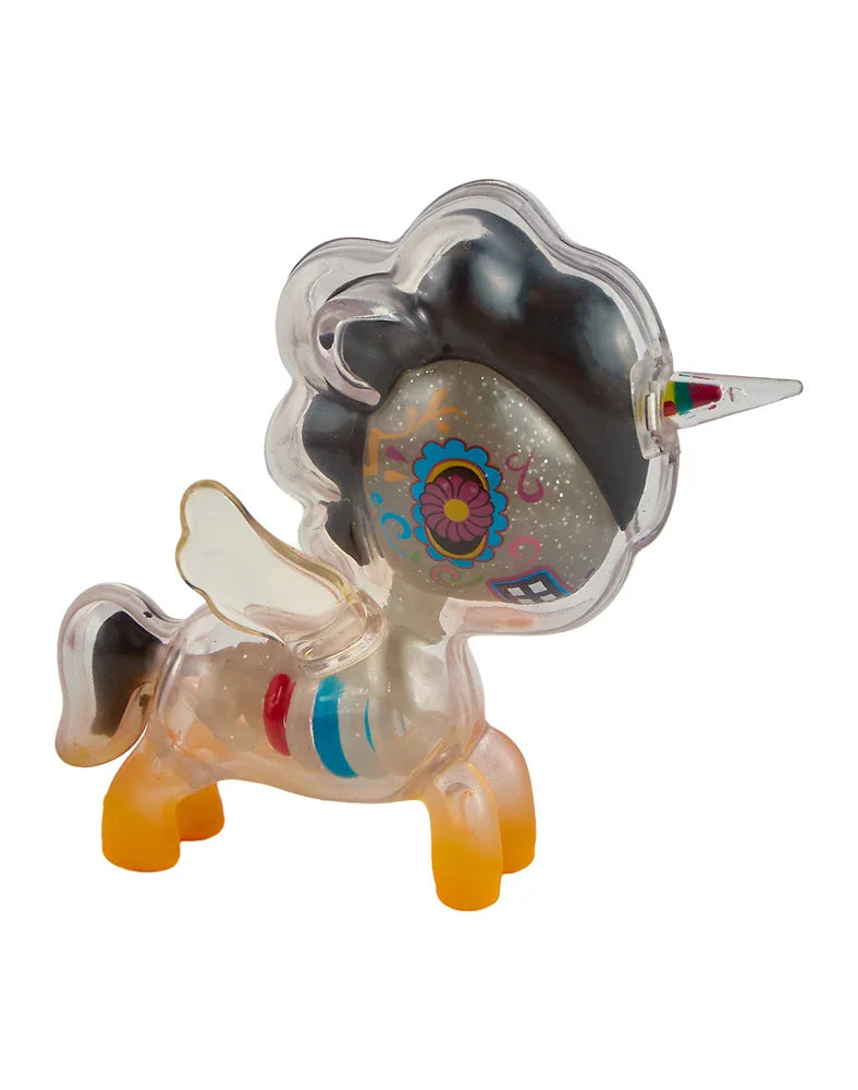 The After Dark Skeleton Unicorno - Caramelo (Special Edition) from tokidoki is a collectible toy figure featuring a transparent body, orange hooves, a rainbow-striped horn, and vibrant face markings—including a floral motif and decorative patterns—with mesmerizing glow-in-the-dark accents for an enchanting display.