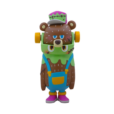 The Rotofugi BG Bear x Frankenskid is a colorful toy figure with blue overalls, green shirt, pink shoes, stitched green and purple hat by Foon Wong, and yellow wheels on its head.