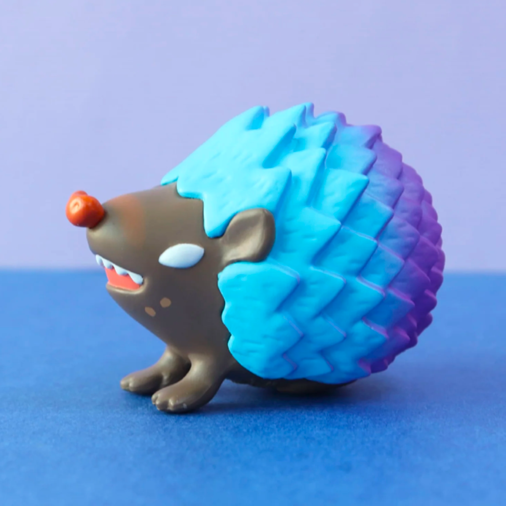 Featuring a hedgehog design with a brown face and vibrant blue and purple spikes, the Good Hedgehog/Bad Hedgehog Blind Box by Partner Toys showcases a pure-hearted figure against its color-coordinated background.