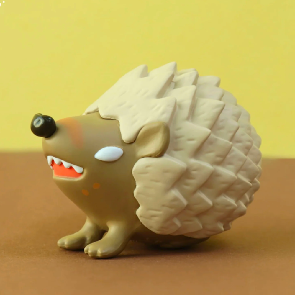 A small figurine depicting a cartoon-style hedgehog with an open mouth, embodying purity of heart, is set against a yellow and brown backdrop. This is part of the 