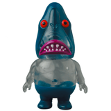 A Vag 35 - Samen Chu toy shark with a red mouth and blue eyes sits on the shelf.