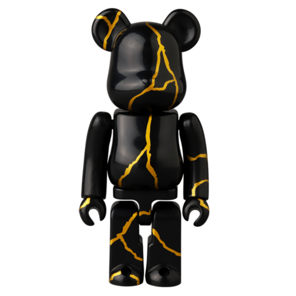 The Be@rbrick Series 49 Blind Box by Medicom (JP) features a black bear-shaped figurine adorned with golden crack-like lines, standing upright against a plain background, embodying the thrill of discovery as a blind box collectible.