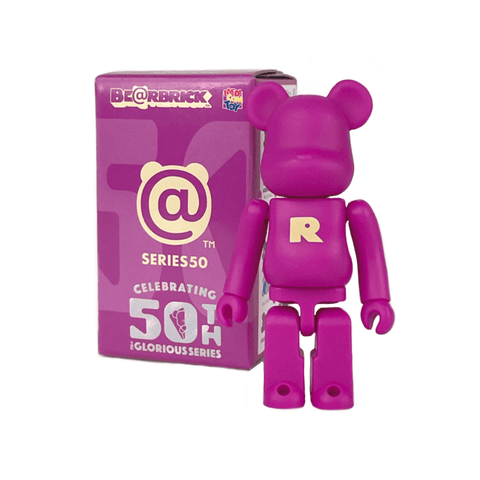 A purple Bearbrick figure with a yellow "R" on its chest stands next to a Medicom (JP) Be@rbrick Series 50 Blind Box that reads “Celebrating 50th Glorious Series.”.